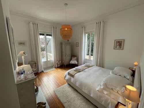 a bedroom with a white bed in a room with windows at Le Lierre et La Rose in LʼAigle