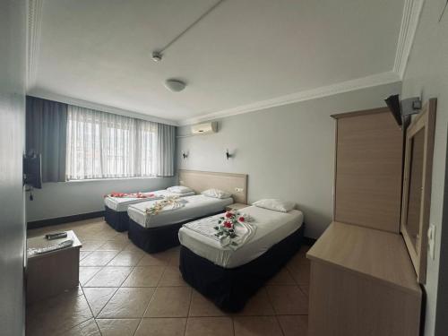 ein Hotelzimmer mit zwei Betten mit Blumen darauf in der Unterkunft Kaunos Hotel in Koycegiz