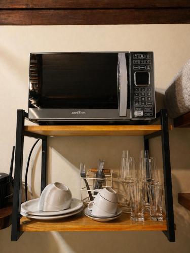 a microwave on a shelf with plates and glasses at Refúgios de Mauá - Chalé Serra in Visconde De Maua