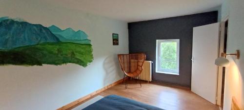 a room with a painting on the wall and a chair at Chambres d'hôtes Las Carbounieros in Auriac