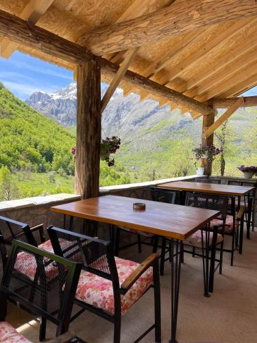 a room with tables and chairs with a view of mountains at A&R cottages in Vusanje