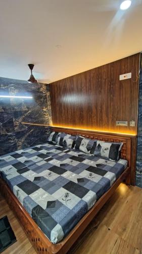 a checkered bed in a room with a wooden wall at SIU Elite INN in Chennai