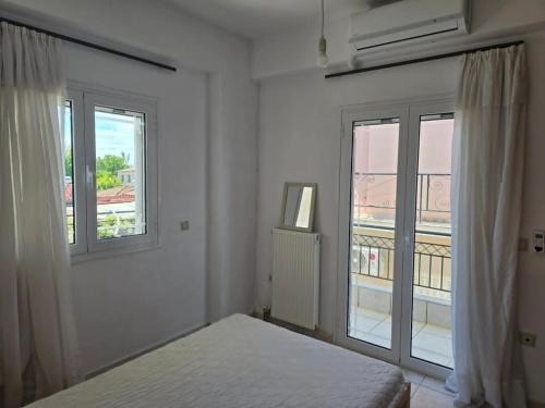 a white bedroom with a bed and two windows at Nature & Sea Paradise in Analipsi in Análipsis