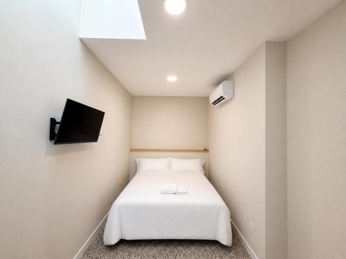 a bedroom with a white bed and a flat screen tv at Hostal Majadahonda in Majadahonda