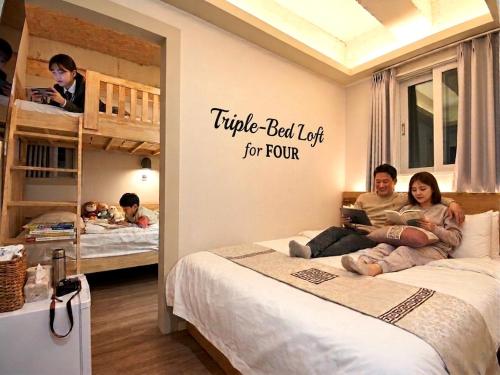 a man and woman sitting on a bed in a room with bunk beds at Hotel Soda STAY in Seoul