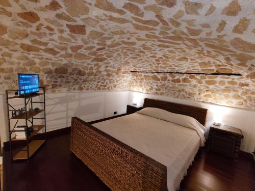 a bedroom with a bed and a stone wall at Almarè Confort Rooms in Terrasini