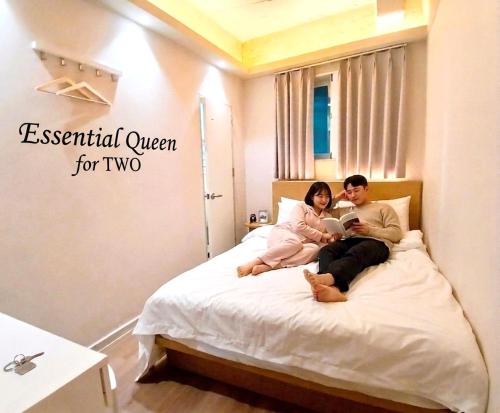 a man and woman sitting on a bed with a tablet at Hotel Soda STAY in Seoul