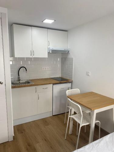 a kitchen with white cabinets and a table and chairs at BEACH Arguineguin FIRST LINE CHG FAMILY HOTEL in Arguineguín