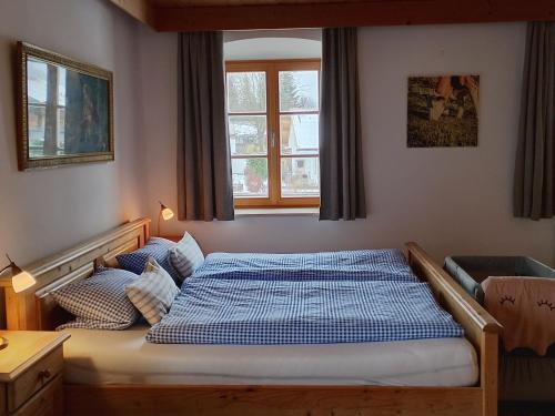 a bedroom with a bed with a blue and white comforter at Haiderhof in Schleching