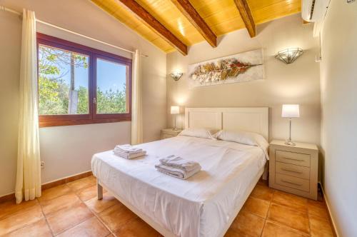 a bedroom with a white bed and a window at Finca Cas Padrins in Manacor