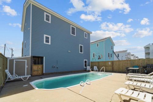 a building with a swimming pool next to a house at 5319 - Day Dreamz in Kill Devil Hills