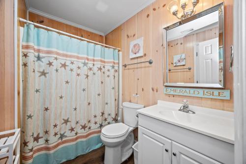 a bathroom with a toilet and a sink and a shower curtain at Paradise East by Emerald Isle Realty in Emerald Isle