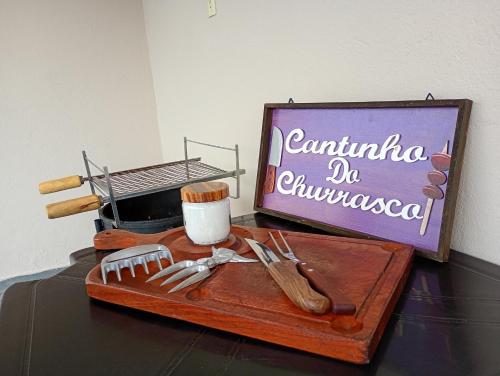 a wooden cutting board with utensils on a table at Refúgio Aura,casa com suíte, wi-fi, garagem e churrasqueira in Aparecida