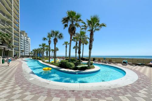 a pool at the beach with palm trees and the ocean at Phoenix West 2207 Upscale Luxury Updated Beachfront Waterslide-Lazy River in Orange Beach