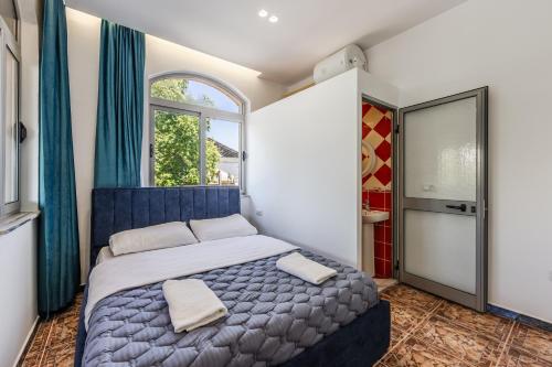 a bedroom with a blue bed and a window at Shiroka Stays in Shirokë
