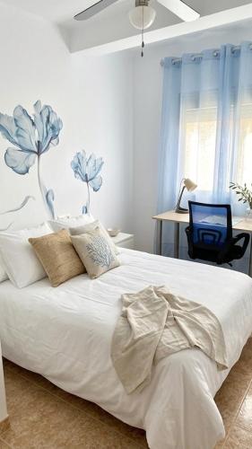 a bedroom with a white bed with blue flowers on the wall at Apartamento EL SOL DEL ZAPILLO in Almería