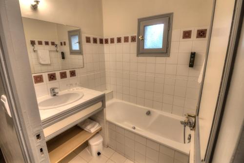 a white bathroom with a tub and a sink at Logis Hôtel Le Moulin de la Beune in Les Eyzies-de-Tayac