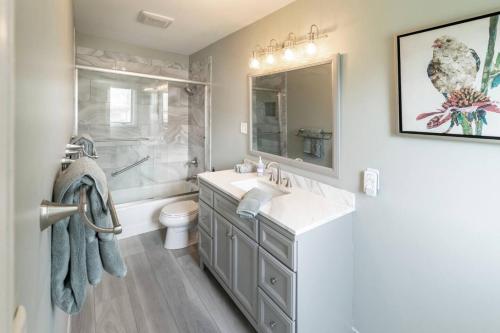 a bathroom with a sink and a toilet and a mirror at Spacious 4 BR 3 BA with Fenced Yard in Shawnee