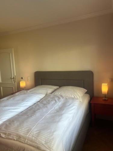a bed with two white pillows and two lamps at Dünenhaus Garten in Timmendorfer Strand