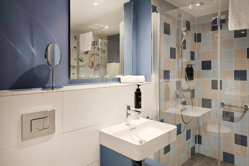 a bathroom with a sink and a mirror at Holiday Inn - the niu, Quay Hamburg Harburg by IHG in Hamburg