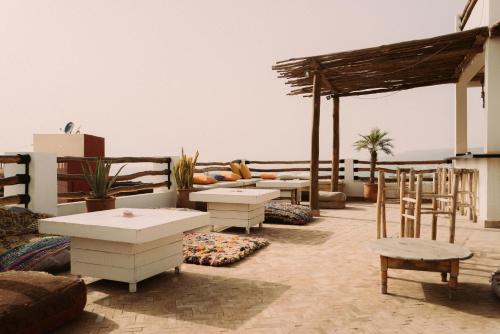 a patio with tables and chairs and a view of the ocean at Surf and Friends in Tamraght Ou Fella