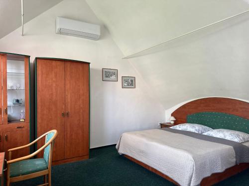 ein Schlafzimmer mit einem Bett, einem Stuhl und einem Schrank in der Unterkunft Apartman Reduta in Lučenec