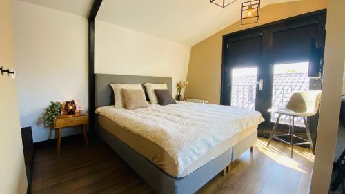a bedroom with a large bed and a chair at Family holiday home by beach and forest in Dirkshorn
