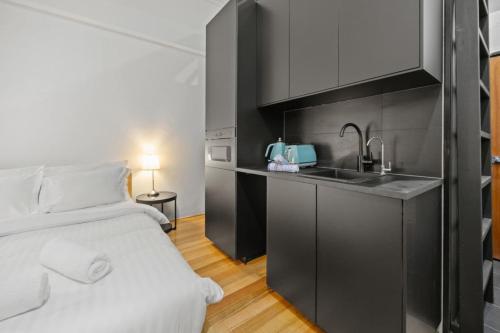 a bedroom with a bed and a kitchen with a sink at South Beach Studio - Simple Base, Walk Everywhere in South Fremantle