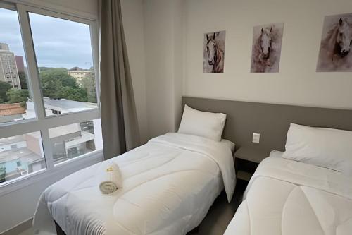 two beds in a room with a window at Edificio Elegance in Foz do Iguaçu
