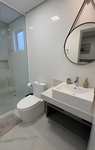 a bathroom with a toilet and a sink and a mirror at Edificio Elegance in Foz do Iguaçu