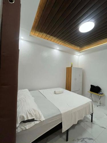 a bedroom with a white bed with a wooden ceiling at Watermelon apartment in San Isidro
