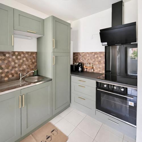 a kitchen with gray cabinets and a sink and a microwave at T2 moderne avec terrasse, central et calme in Saint-Herblain