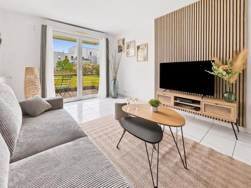 a living room with a television and a table at T2 moderne avec terrasse, central et calme in Saint-Herblain