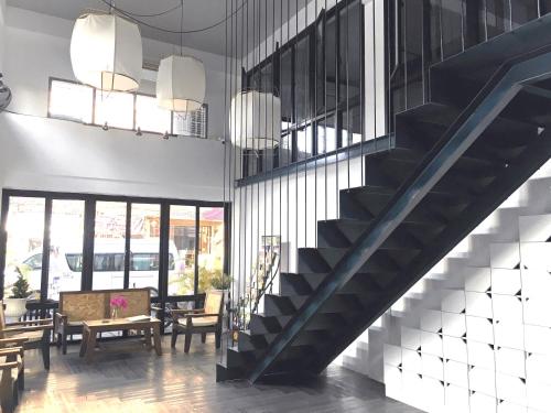 a lobby with a staircase and a table and chairs at The August Hostel in Chiang Mai