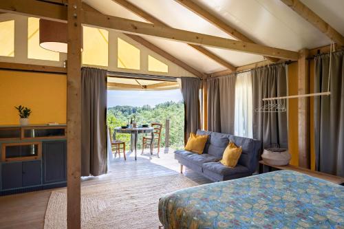 a bedroom with a bed and a couch and a table at Glamping Stregaia in Massa Marittima