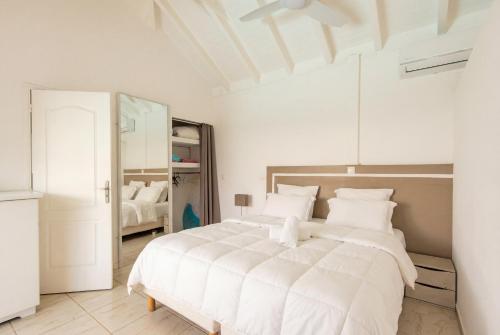 a white bedroom with a large white bed with white pillows at Location Dampierre in Le Gosier