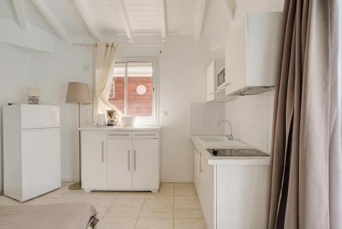 a white kitchen with a sink and a refrigerator at Location Dampierre in Le Gosier