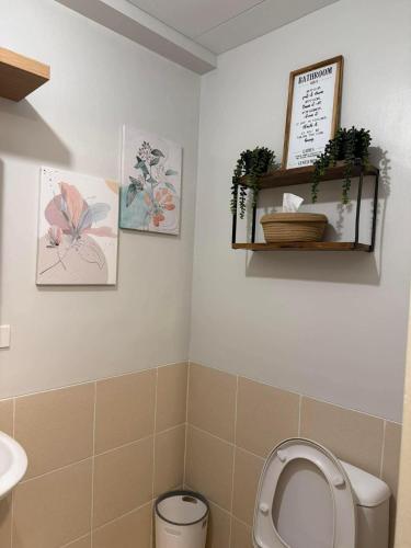 a bathroom with a toilet and two pictures on the wall at Verdon Parc condominium in Davao City