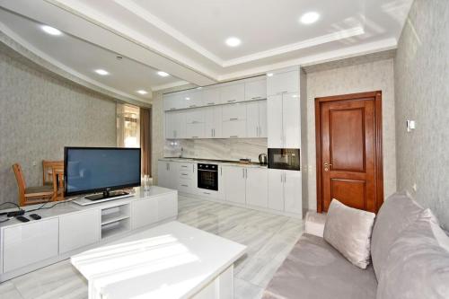 a large white kitchen with a couch and a tv at Elite & Grand Luxury Hotel Apartments in Central Yerevan, By Opera and Northern Avenue in Yerevan
