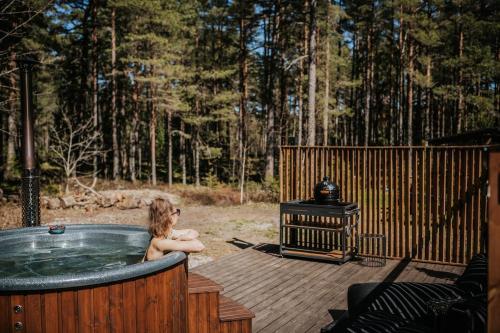 a woman sitting in a hot tub on a deck at Üleoja Pesa in Kloogaranna