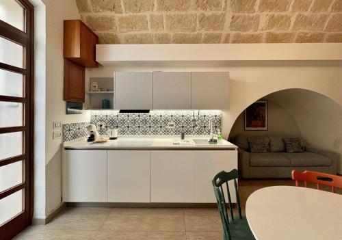 a kitchen with white cabinets and a couch at I quattro Pumi in Mola di Bari