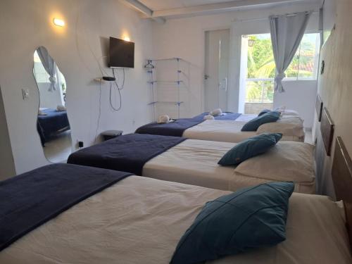 a room with four beds and a window at POUSADA PARAISO da BARRA DA TIJUCA in Rio de Janeiro
