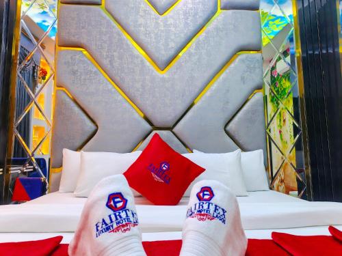 a persons feet on a bed with red pillows at Fairtex Luxury Hotel in Lekki