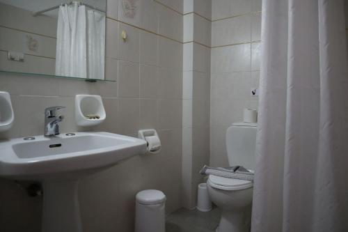 a white bathroom with a sink and a toilet at Platanes Hotel Apartments Rethymno in Platanes