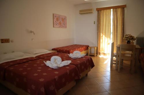 two beds in a hotel room with flowers on them at Platanes Hotel Apartments Rethymno in Platanes