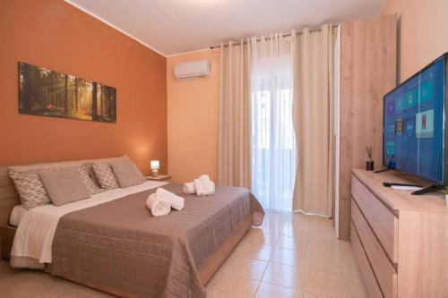 a bedroom with a bed and a flat screen tv at Kleos Apartment in Schisò