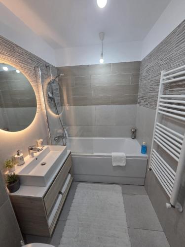 a bathroom with a tub and a sink and a mirror at Wonderful Apartment in Braşov