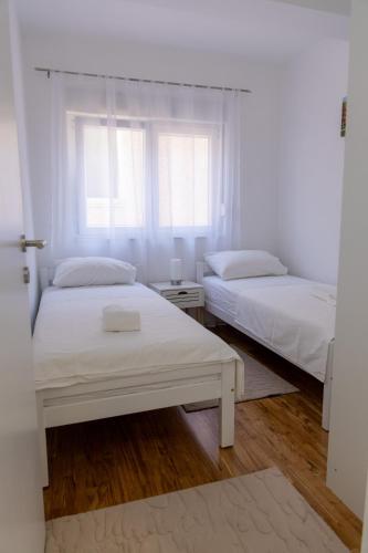 two beds in a white room with a window at Apartment LANA in Čapljina