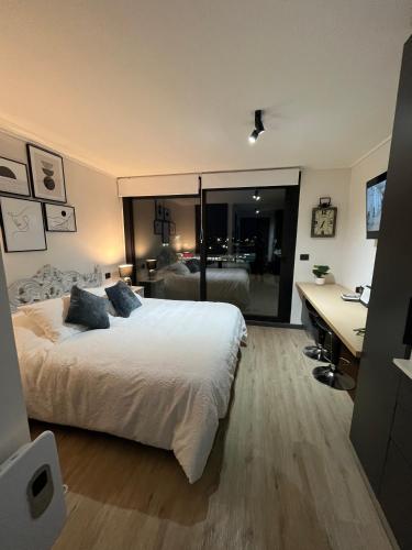 a bedroom with a bed and a desk with a computer at Ápice del bosque in Temuco