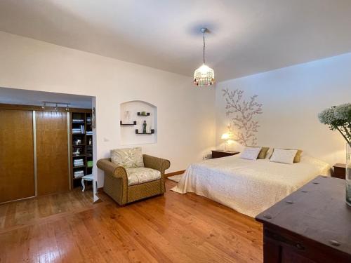 a bedroom with a bed and a chair in it at Casa dos Cedros in Bicas